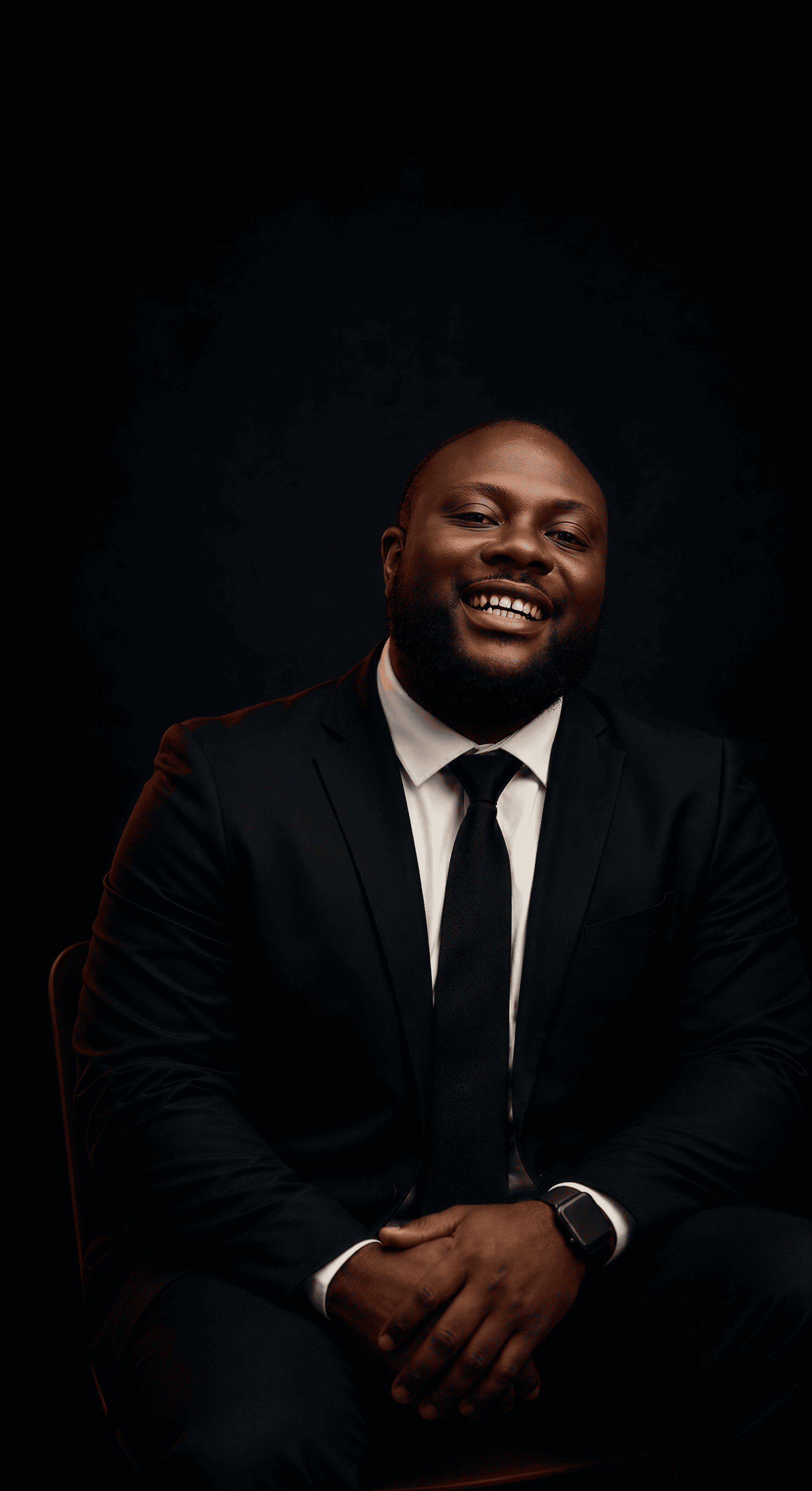 A professional, high-contrast studio portrait of a charismatic West African marketing executive in a modern charcoal suit. The lighting is dramatic and moody with deep void backgrounds and subtle red rim lighting. The subject projects authority and confidence, set against a dark, editorial aesthetic consistent with premium brand leadership.